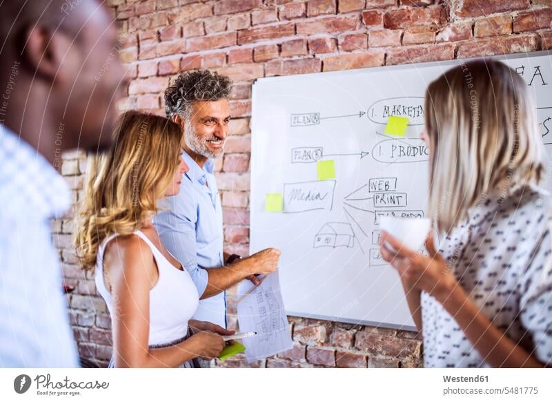 Business team working together on whiteboard at brick wall in office white board brick walls At Work business business world business life offices office room