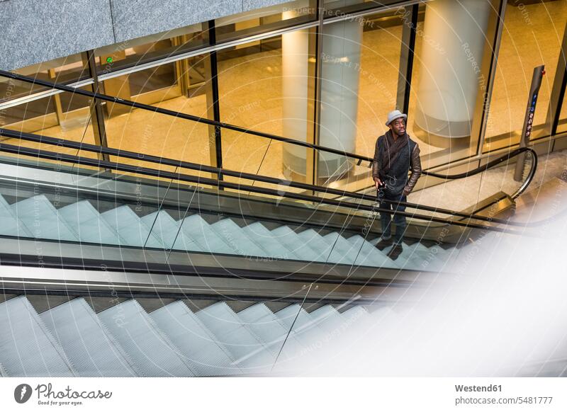 Young man standing on escalator looking around moving staircase moving stairs Escalators men males Adults grown-ups grownups adult people persons human being