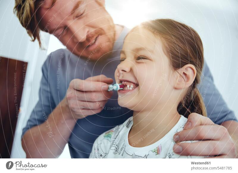 Father brushing daughter’s teeth in bathroom toothbrush tooth-brushes toothbrushes father pa fathers daddy dads papa daughters brushing teeth parents family
