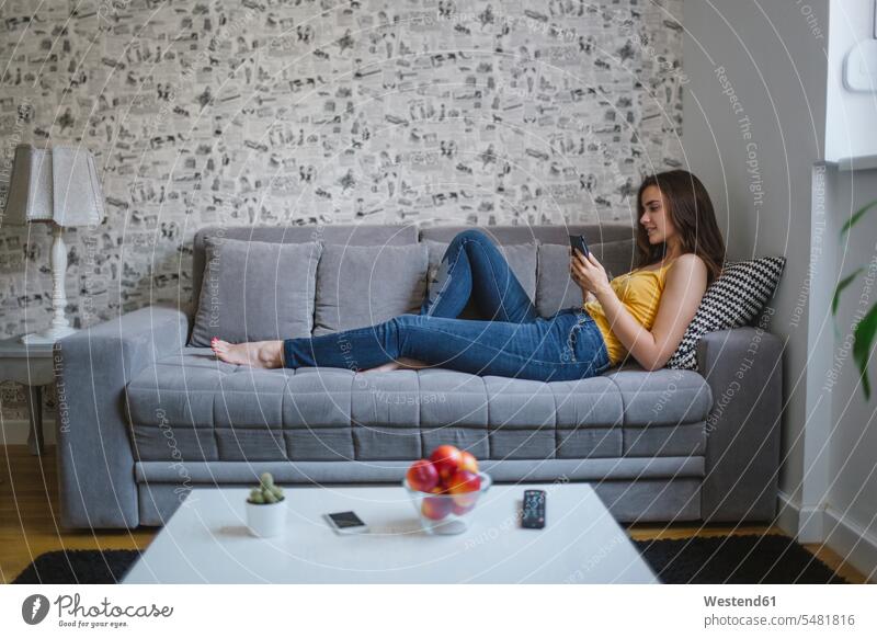 Woman on couch in the living room reading e-book woman females women Adults grown-ups grownups adult people persons human being humans human beings settee sofa