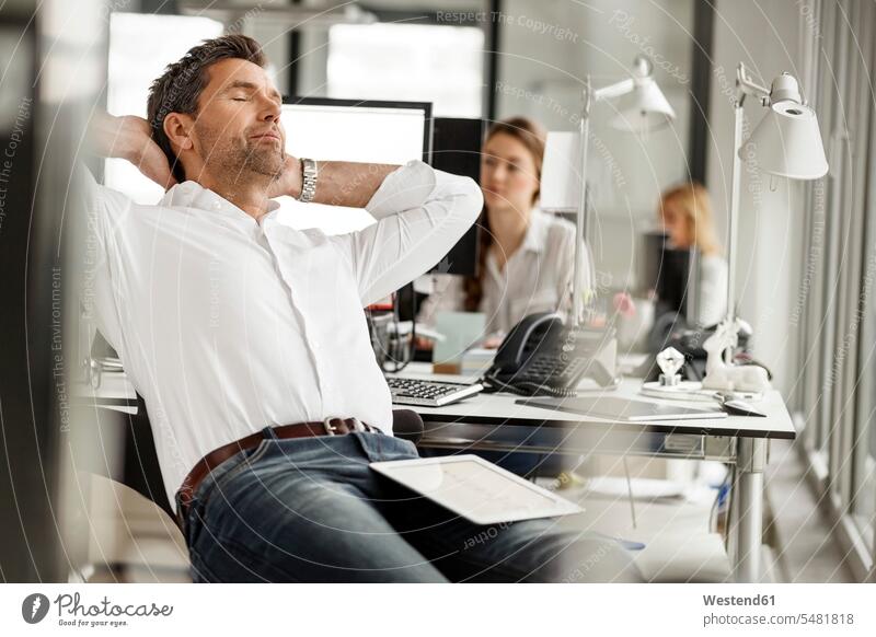Businessman relaxing at desk in office relaxed relaxation offices office room office rooms Business man Businessmen Business men workplace work place