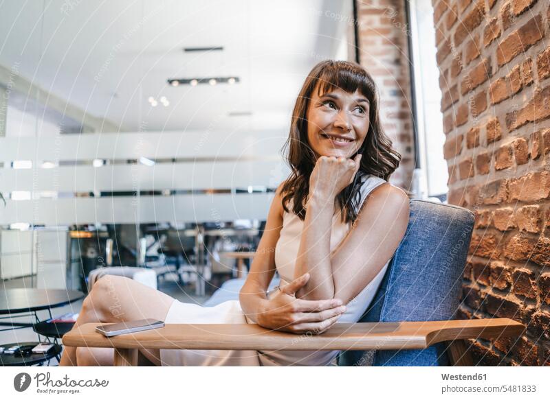 Businesswoman sitting on couch in office, smiling Seated smile Office Offices Taking a Break resting break businesswoman businesswomen business woman