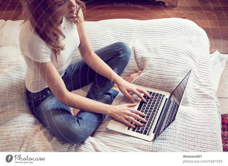Redheaded woman sitting on bed using laptop females women Laptop Computers laptops notebook Adults grown-ups grownups adult people persons human being humans