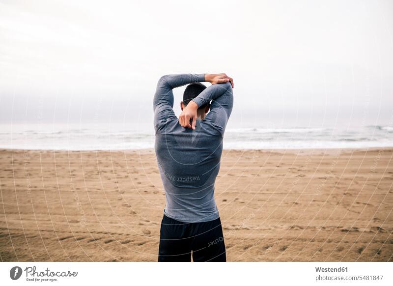 Sportive young man stretching on the beach Spain Preparation prepare preparing nature natural world cloudy cloudiness clouds day daylight shot daylight shots