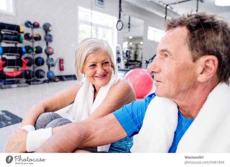 Smiling mature woman and senior man having a break in fitness gym senior adults seniors old smiling smile gyms Health Club couple twosomes partnership couples