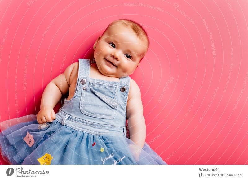 Portrait of smiling baby girl lying on pink background infants nurselings babies laying down lie lying down smile portrait portraits Pink background