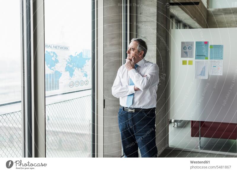 Businessman looking at windowpane with world map in office world maps Business man Businessmen Business men business people businesspeople business world