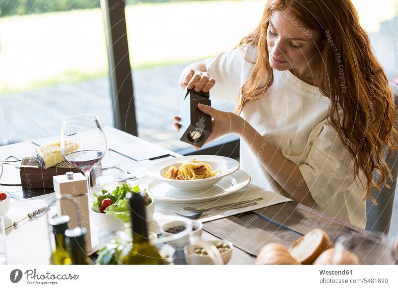 Woman seasoning her spaghetti carbonara woman females women eating enjoying indulgence enjoyment savoring indulging Spaghetti flavouring pepper grinder