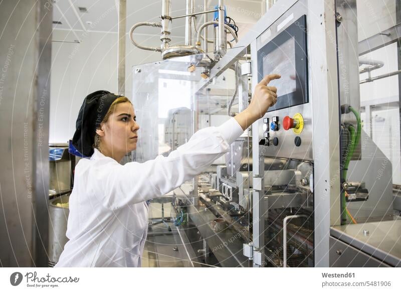 Woman operating a machine during the making of chocolate in a factory factories working At Work woman females women Adults grown-ups grownups adult people