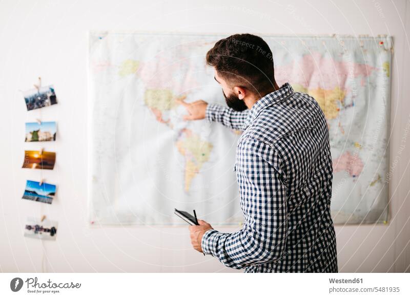 Young man selecting travel destinations on a world map caucasian caucasian ethnicity caucasian appearance european casual leisure wear casual clothing