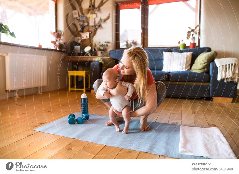 Mother with baby and dumbbells at home exercising exercise training practising infants nurselings babies Hand Weight Hand Weights mother mommy mothers ma mummy