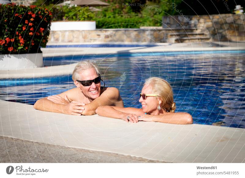Happy senior couple in swimming pool resort resort town enjoying indulgence enjoyment savoring indulging together Young at Heart youthful Lifestyles pensioner