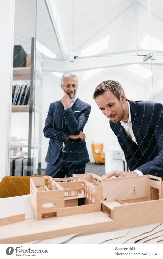 Two businessmen examining architectural model in office models offices office room office rooms architects smiling smile scrutiny scrutinizing Businessman