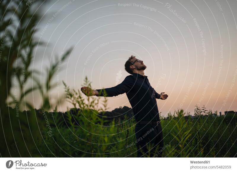 Businessman standing in rural field at sunset business life business world business person businesspeople Business man Business men Businessmen human