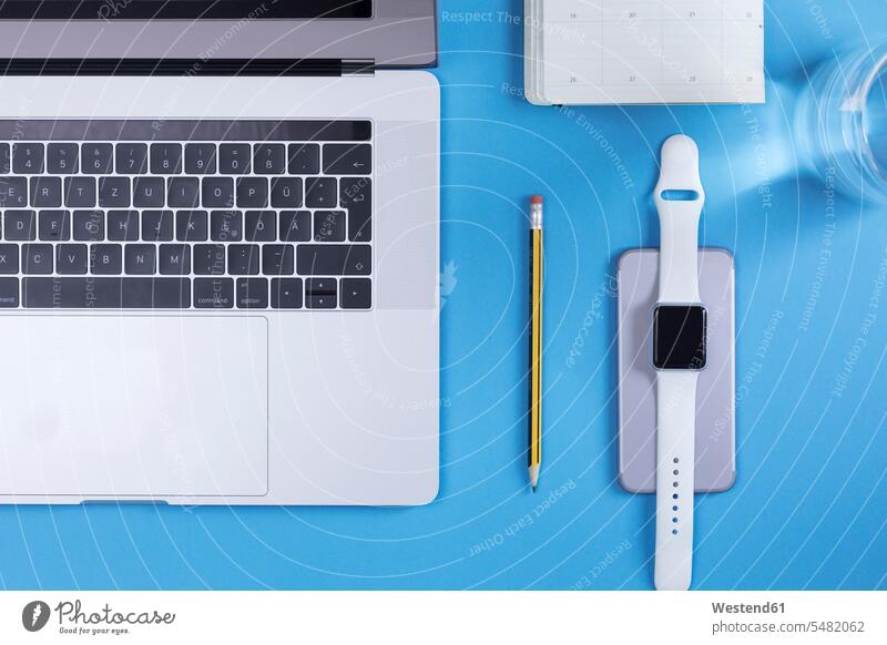 Various electronic devices, personal organizer, pencil and glass of water on blue ground business business world business life mobile working Planning planning