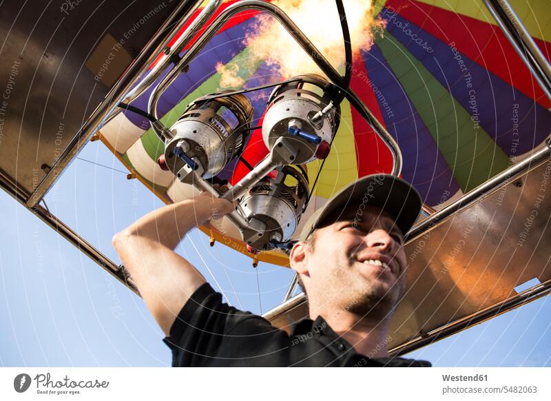 Man using burners of a hot air balloon man men males ballooning Flame Blaze balloons air balloons Adults grown-ups grownups adult people persons human being