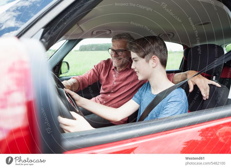 Father teaching son driving a car car driving motoring smiling smile educating educate practicing practice practise exercise exercising practising sons manchild
