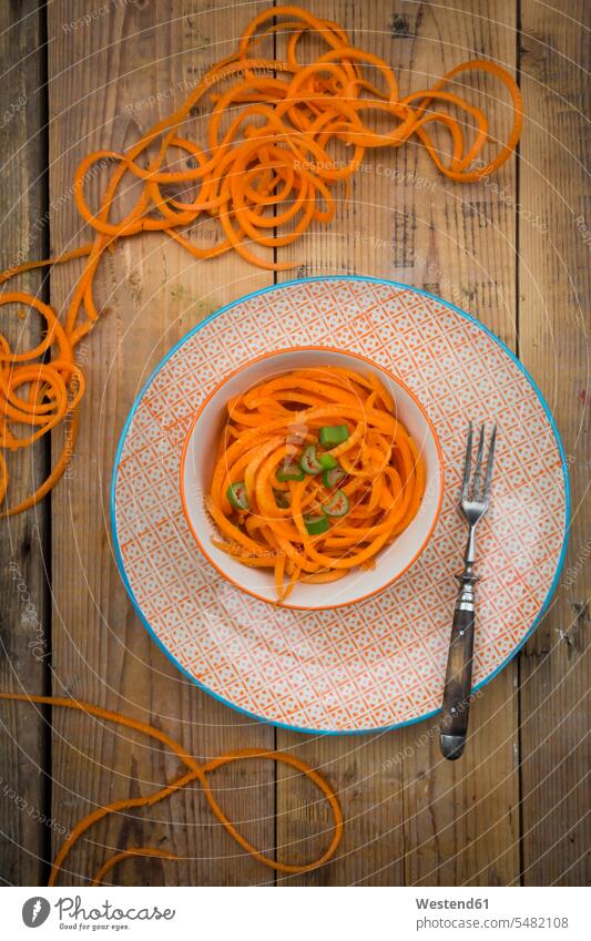 Bowl of spiralized carrot salad with spring onions Bowls healthy eating nutrition wooden uncooked garnished ready to eat ready-to-eat green onion chopped cut