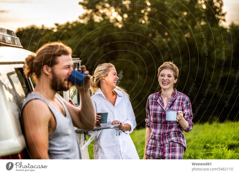 Carefree friends enjoying coffee at a van in rural landscape Coffee mate Fun having fun funny laughing Laughter Drink beverages Drinks Beverage food and drink