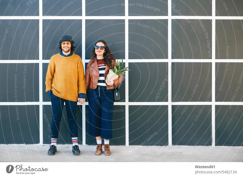 Young couple hand in hand twosomes partnership couples people persons human being humans human beings smiling smile portrait portraits standing holding hands