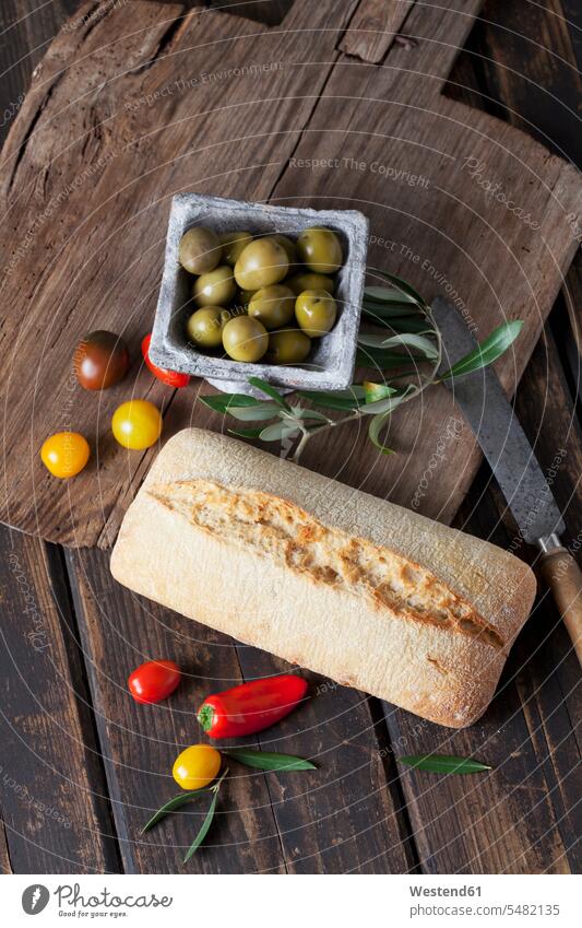 Ciabatta bread with green olives in bowl, tomatoes and mini capsicum on wood nobody Freshness fresh healthy eating nutrition knife knives still life still-lifes