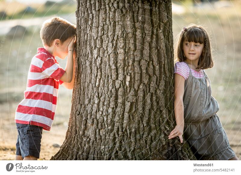Little boy and girl playing hide and seek in nature caucasian caucasian ethnicity caucasian appearance european friends mate day daylight shot daylight shots