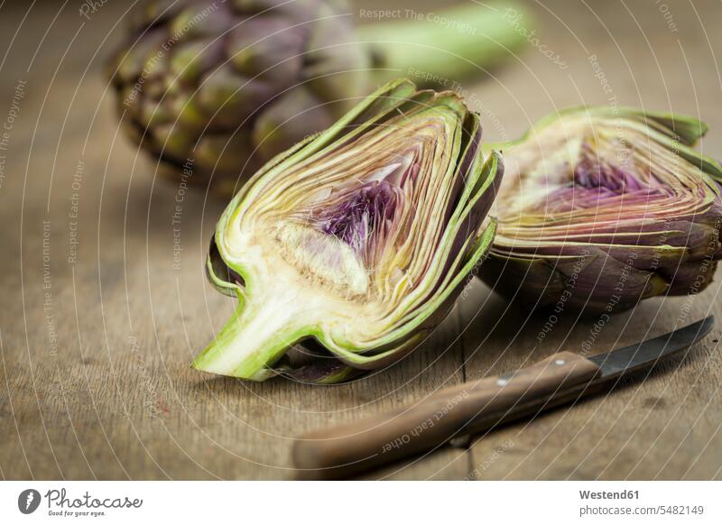 Sliced artichoke and kitchen knife on wood uncooked close-up close up closeups close ups close-ups half halves halved raw textured wooden nobody healthy eating