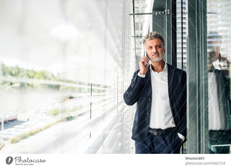 Mature businessman on cell phone at outside sunblind Businessman Business man Businessmen Business men sun-blind jalousie venetian blind venetian blinds