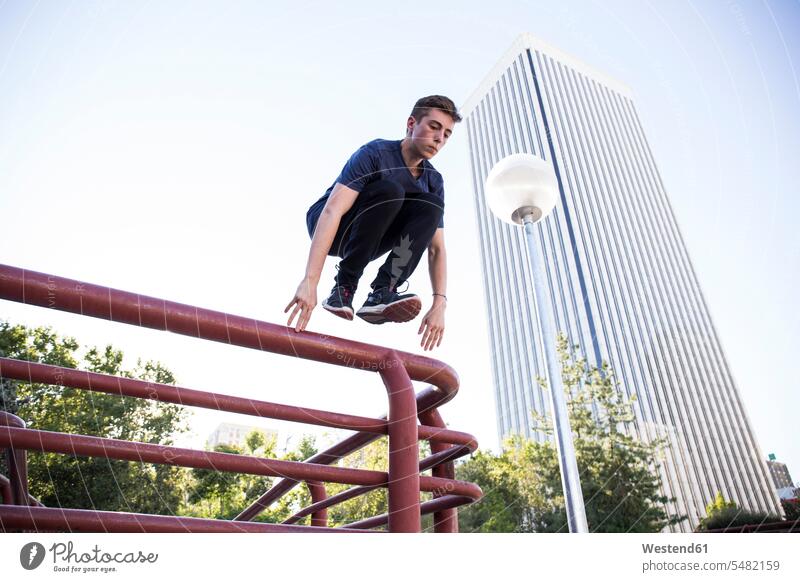 Spain, Madrid, man jumping over a fence in the city during a parkour session active Parkour Free Running Leaping men males leisure free time leisure time sport