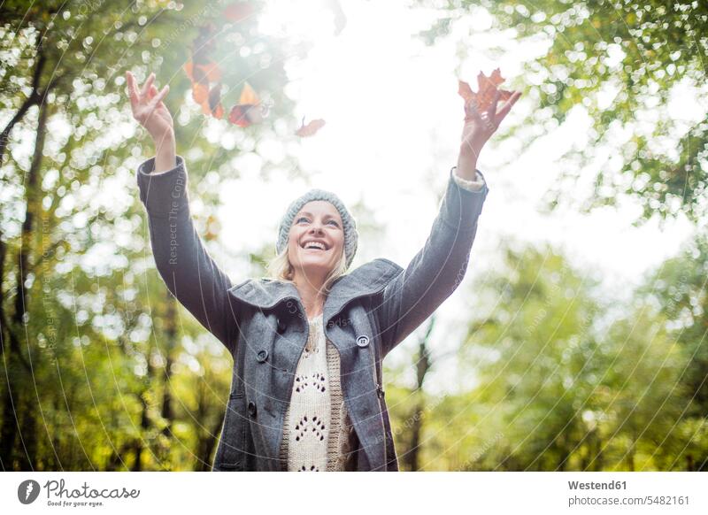 Happy woman in the forest in autumn throwing leaves in the air portrait portraits females women laughing Laughter Adults grown-ups grownups adult people persons