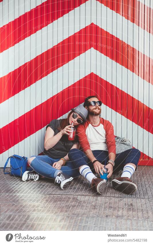 Young couple relaxing on the street content pleased Lifestyles drinking relaxation relaxed red-white red white redwhite Red And White outdoors outdoor shots