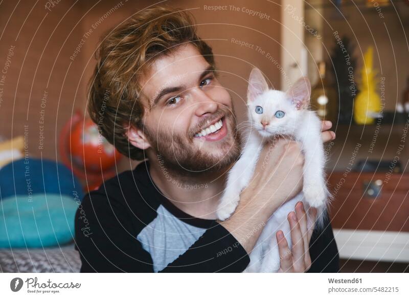 Portrait of smiling young man holding white kitten portrait portraits men males cat cats Adults grown-ups grownups adult people persons human being humans