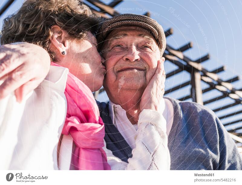 Portrait of happy senior man kissed by his wife peck pecks portrait portraits senior couple elder couples senior couples kissing kisses adult couple
