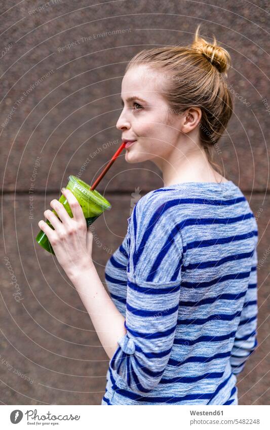 Young woman drinking a smoothie outdoors Smoothies females women Drink beverages Drinks Beverage food and drink Nutrition Alimentation Food and Drinks Adults