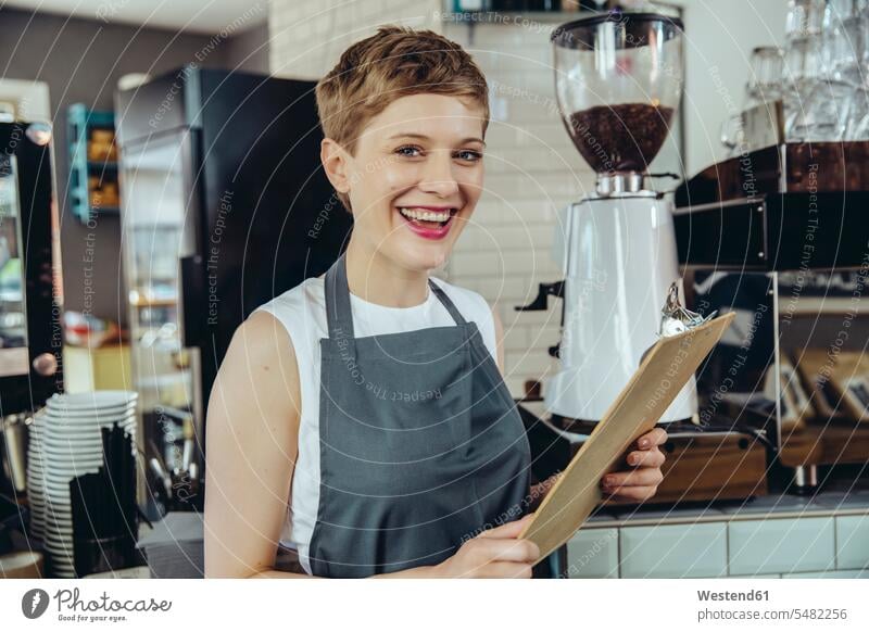 Portrait of laughing waitress holding menu in a cafe waitresses Laughter woman females women portrait portraits waiter server waiters service Wait Staff