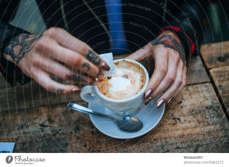 Woman's tattooed hands pouring sugar into cup of coffee, close-up Coffee human hand human hands Drink beverages Drinks Beverage food and drink Nutrition