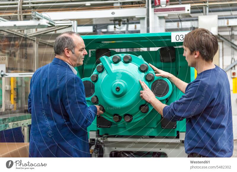 Two people in plastics factory examining machines caucasian caucasian ethnicity caucasian appearance european Cooperation working together collaboration