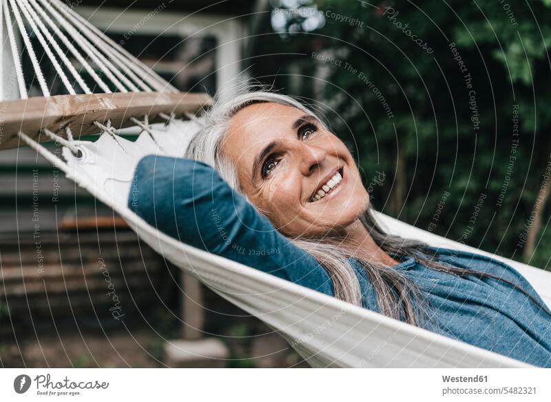 Portrait of smiling woman lying in hammock in the garden hammocks females women happiness happy Adults grown-ups grownups adult people persons human being