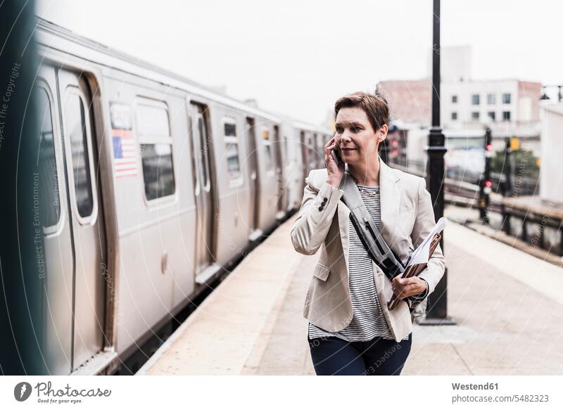Mature woman using smart phone at commuter train station businesswoman businesswomen business woman business women metro the metro Smartphone iPhone Smartphones