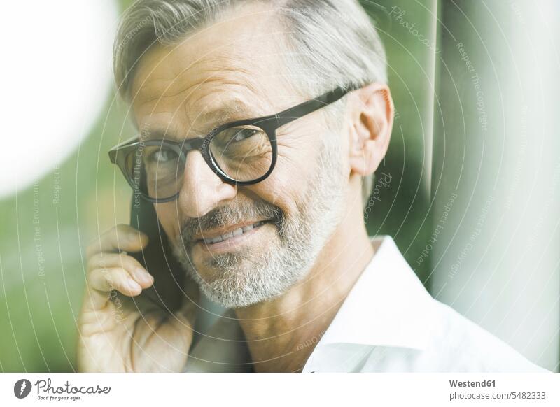 Portrait of smiling man with grey hair and beard on the phone men males portrait portraits Smartphone iPhone Smartphones call telephoning On The Telephone