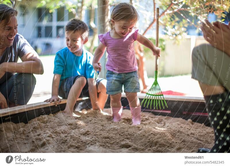 Girl with family playing in sandpit sandbox sandpits sand-box sandboxes sand-boxes girl females girls families father pa fathers daddy dads papa child children