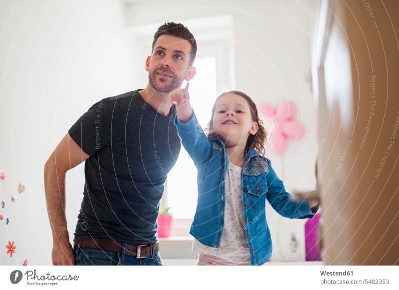 Father with daughter in children's room smiling smile daughters pointing point at pointing at show showing father pa fathers daddy dads papa family families