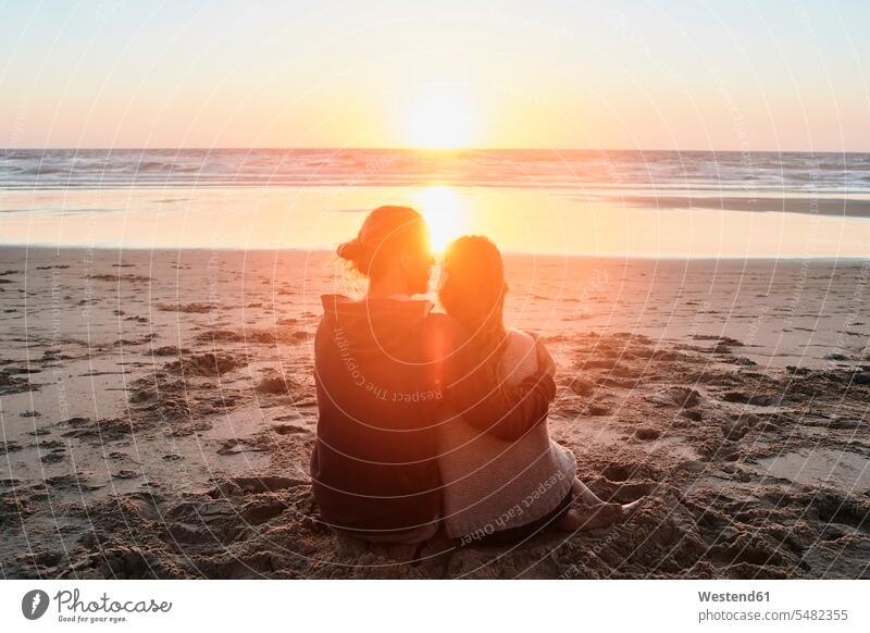 Portugal, Algarve, couple sitting on the beach at sunset happiness happy beaches Seated twosomes partnership couples people persons human being humans