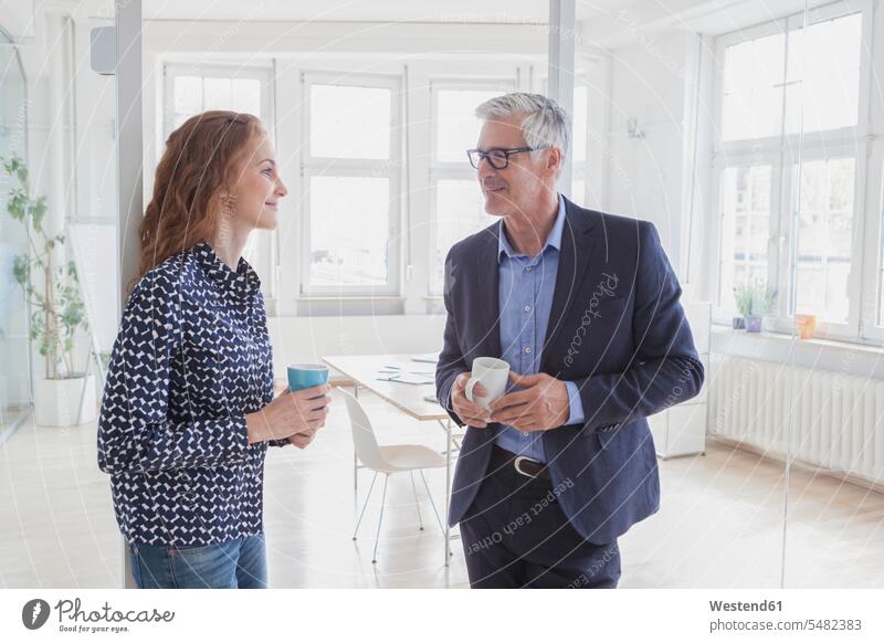 Businessman and woman in office having a coffee offices office room office rooms Business man Businessmen Business men talking speaking Coffee females women