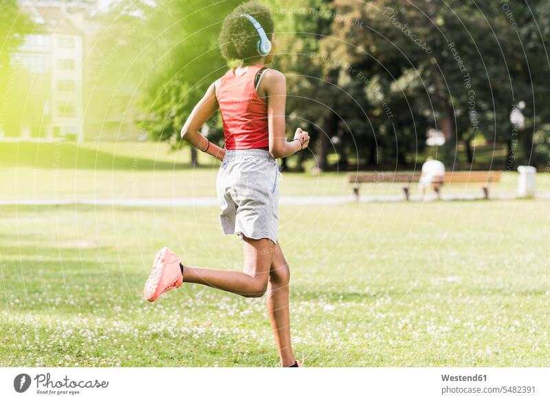Young woman with headphones running in park parks exercising exercise training practising females women headset Jogging Adults grown-ups grownups adult people
