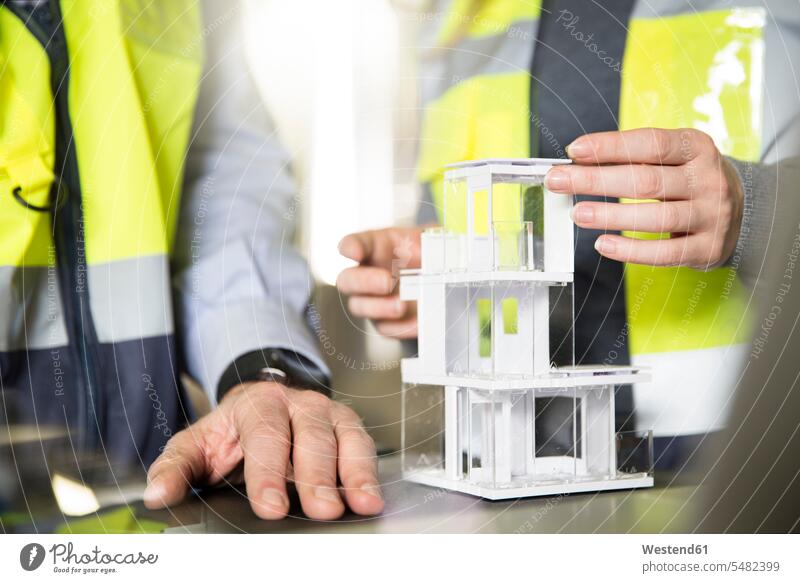 Close-up of colleagues wearing reflective vests with architectural model work wear work clothes workwear female architect architects female architects