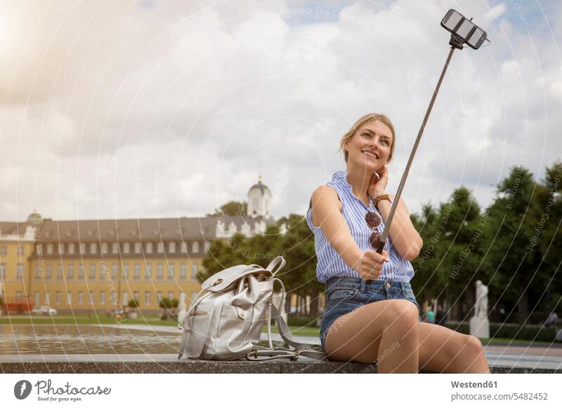 Germany, Karlsruhe, tourist taking selfie with selfie stick Selfie Selfies female tourist Selfie stick woman females women tourists tourism touristic Adults