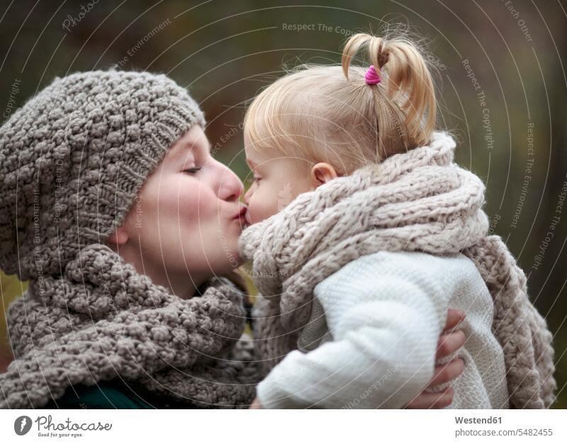 Young woman kissing her little daughter in autumn caucasian caucasian ethnicity caucasian appearance european childhood Head and shoulders upper body