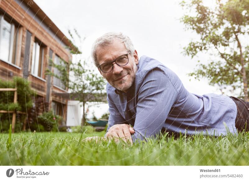 Portrait of smiling mature man lying in garden smile men males gardens domestic garden relaxed relaxation laying down lie lying down Adults grown-ups grownups