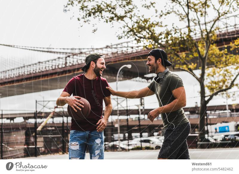 Two young men with basketball having fun on an outdoor court basketballs man males laughing Laughter playing Fun funny friends Basketball sport sports Adults